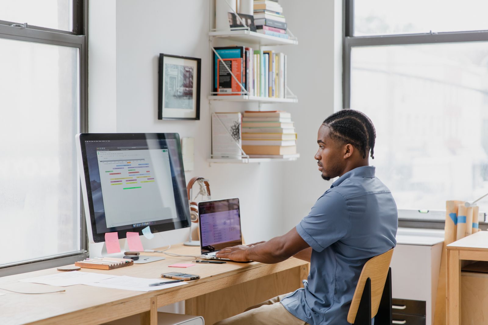A founder working at a desk with a laptop and a large monitor