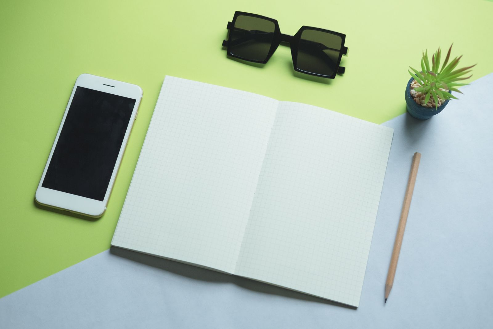 An open notebook, a pencil and a phone on a desk