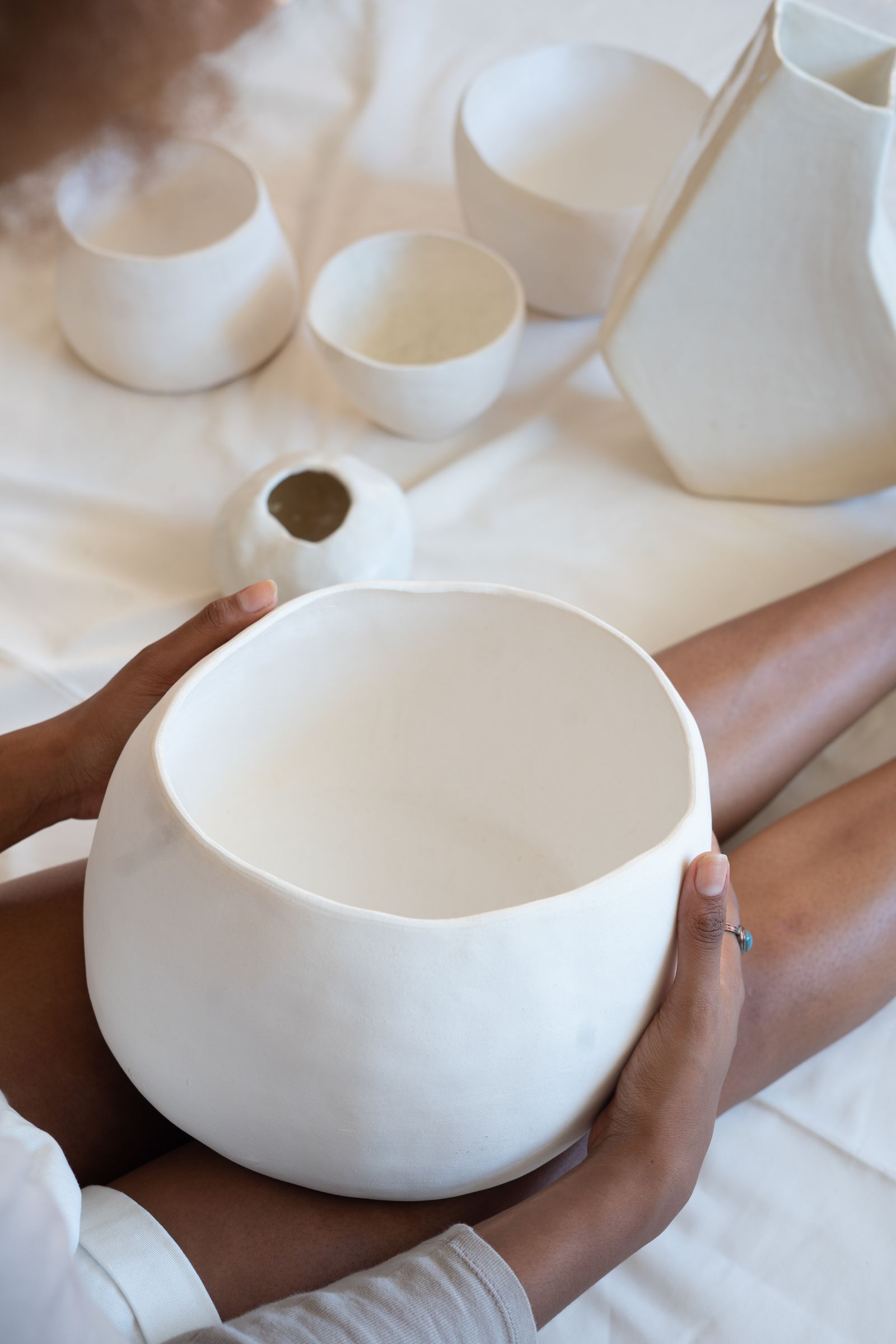 A maker holding a handmade ceramic bowl in her workshop