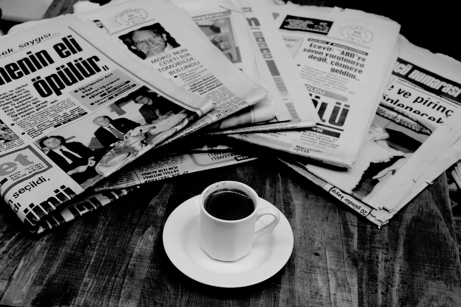 A stack of newspapers next to a cup of coffee