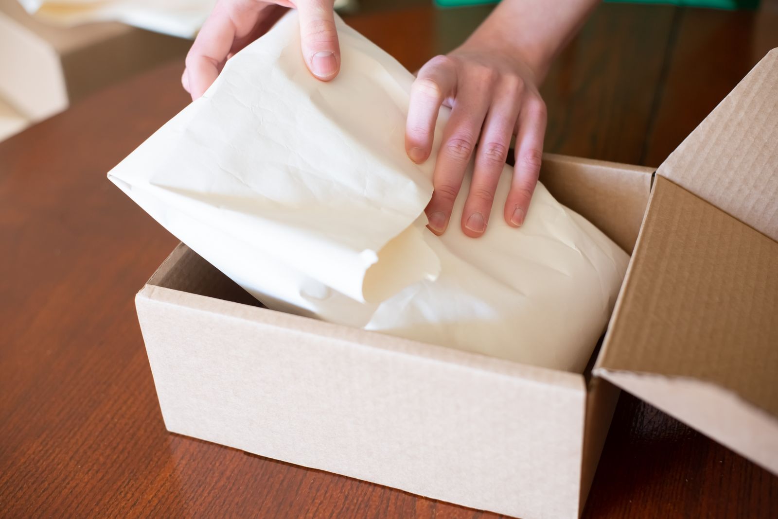 Hands packing a product into a cardboard box